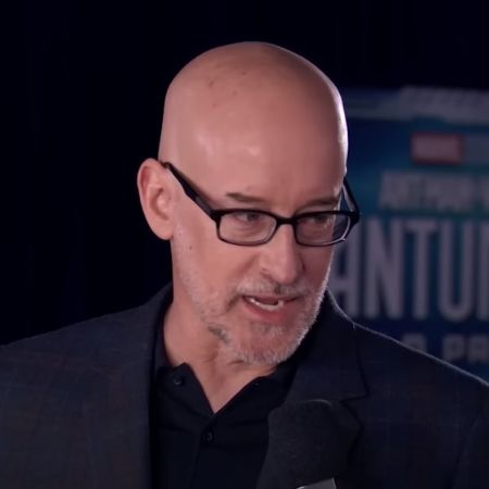 Peyton Reed is wearing a black suit and a shirt with glasses.